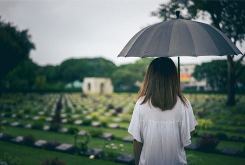 young girl standing in graveyard mourning loss of parent